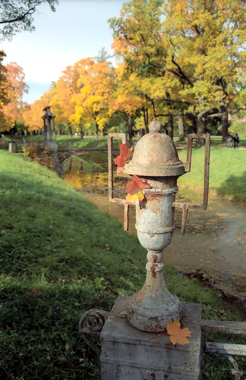 Old shabby metal vase in the autumn park