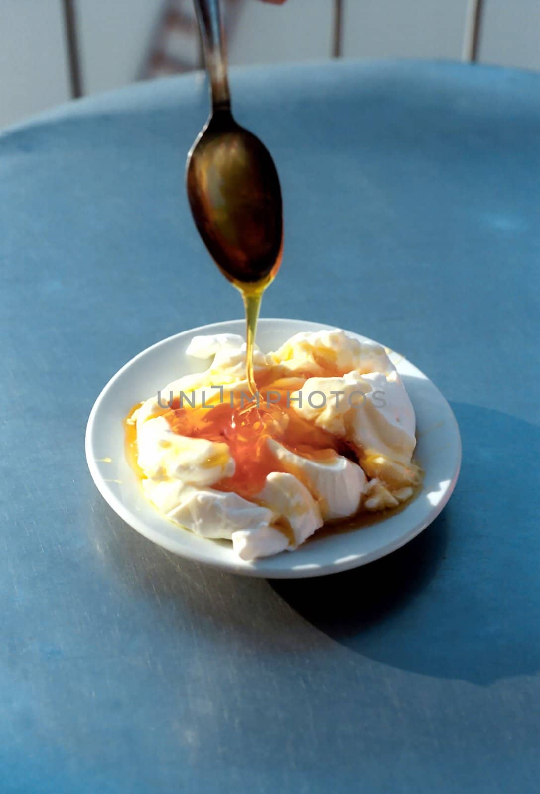 Plate with yoghurt and honey flowing down from spoon