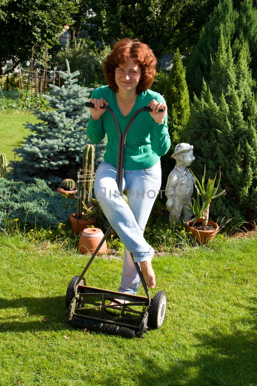 Girl with lawn mower in her garden