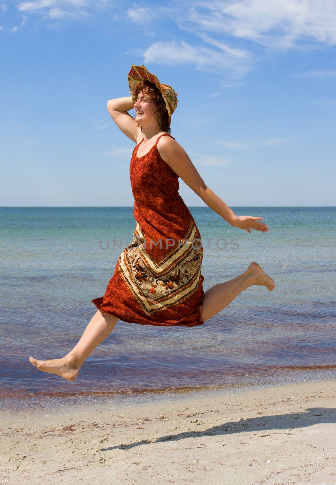 Girl in hat running along snad sea beach