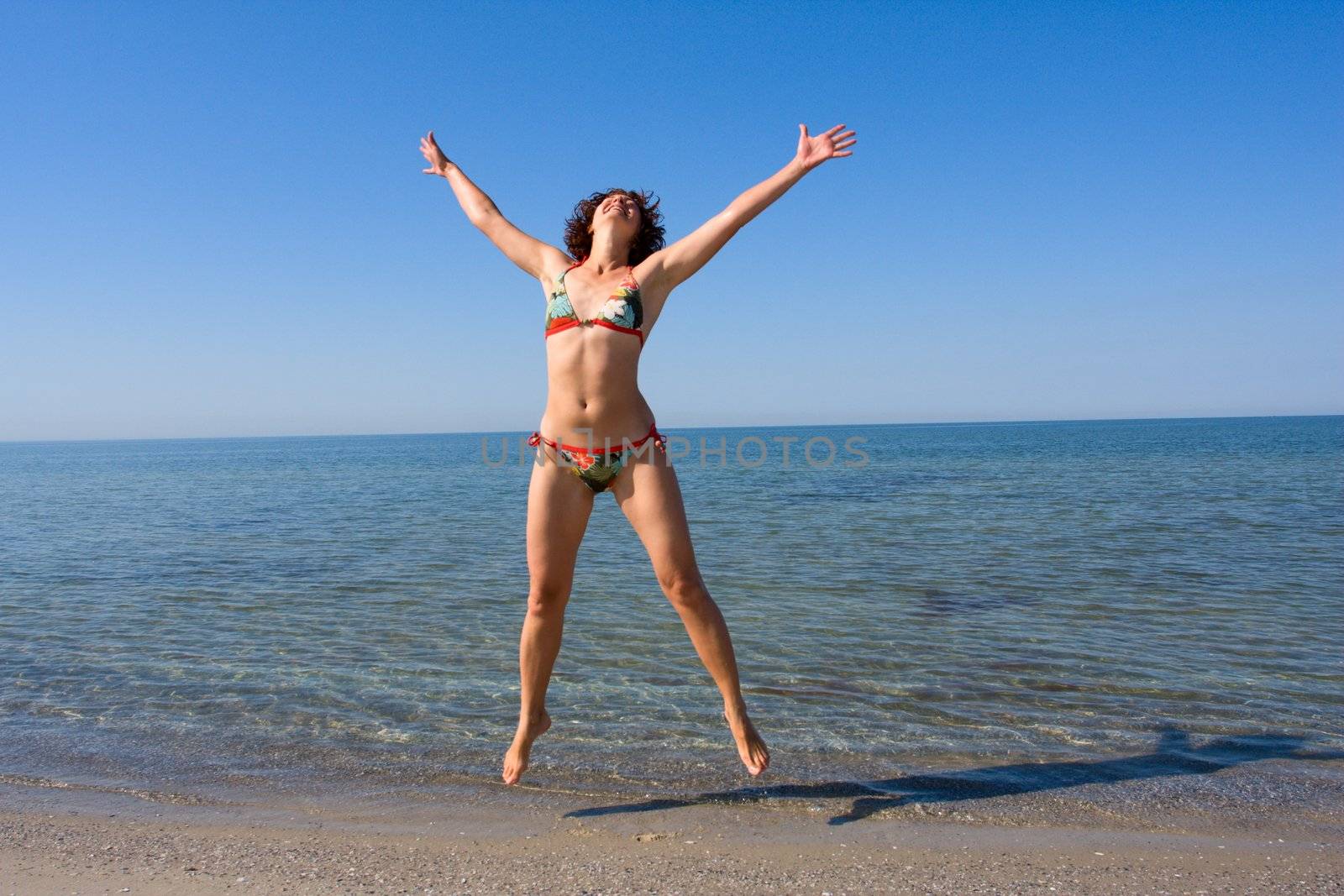 Girl jumping at sand sea beach