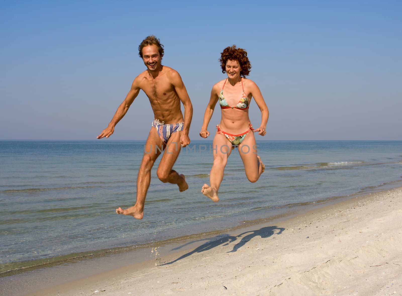 Couple running along sand sea beach