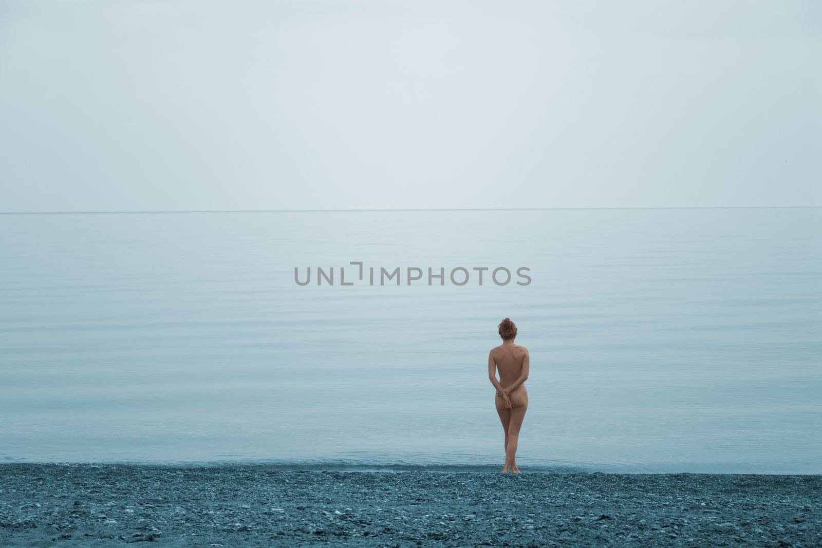 Lonely naked girl on the beach of quite sea