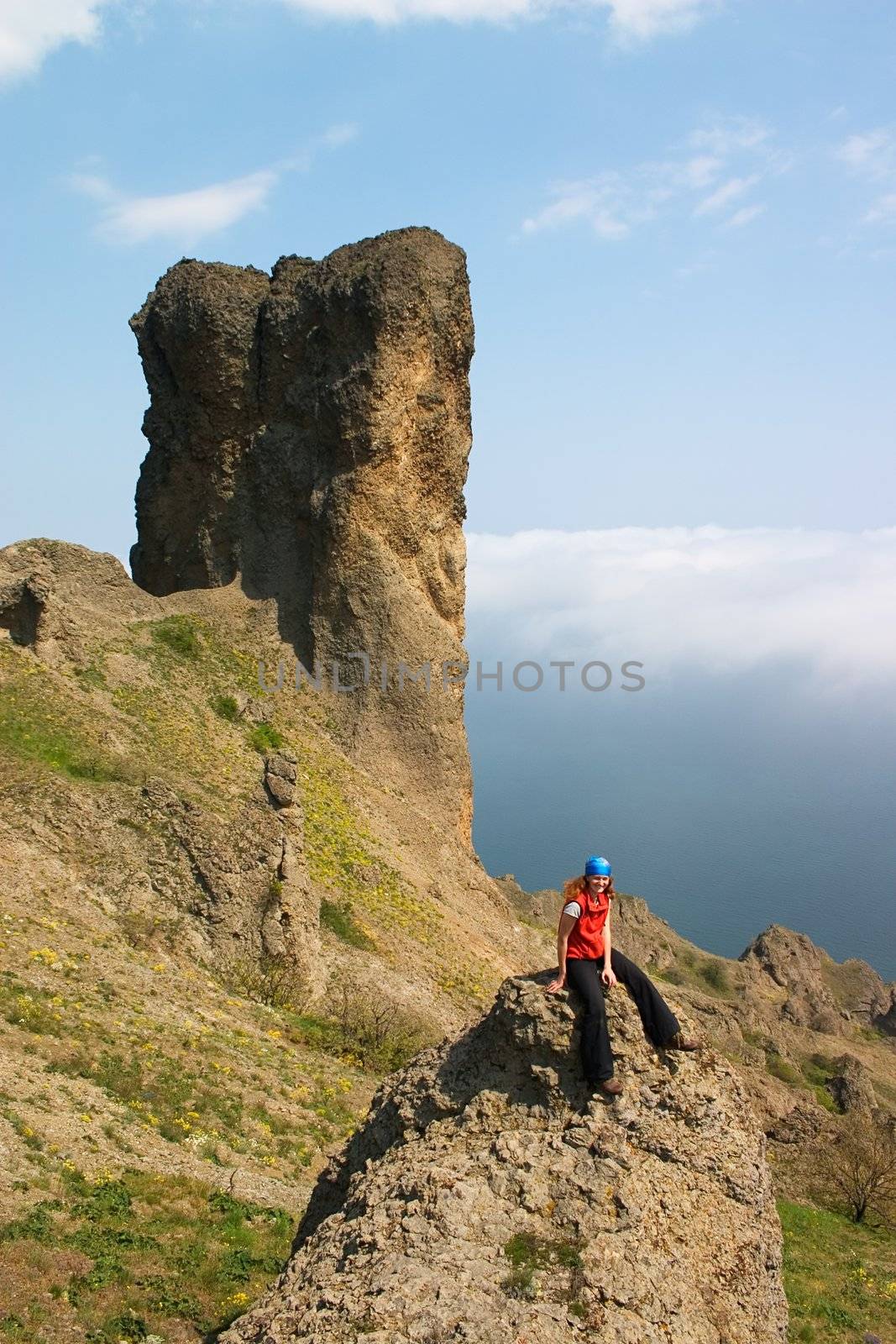 Girl sitting alone on the rock in the mountains 