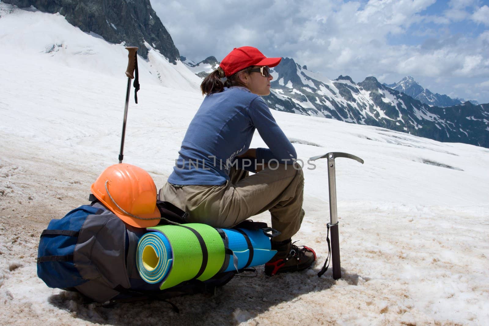 alpinist woman sitting on her backpack in snowy mountains