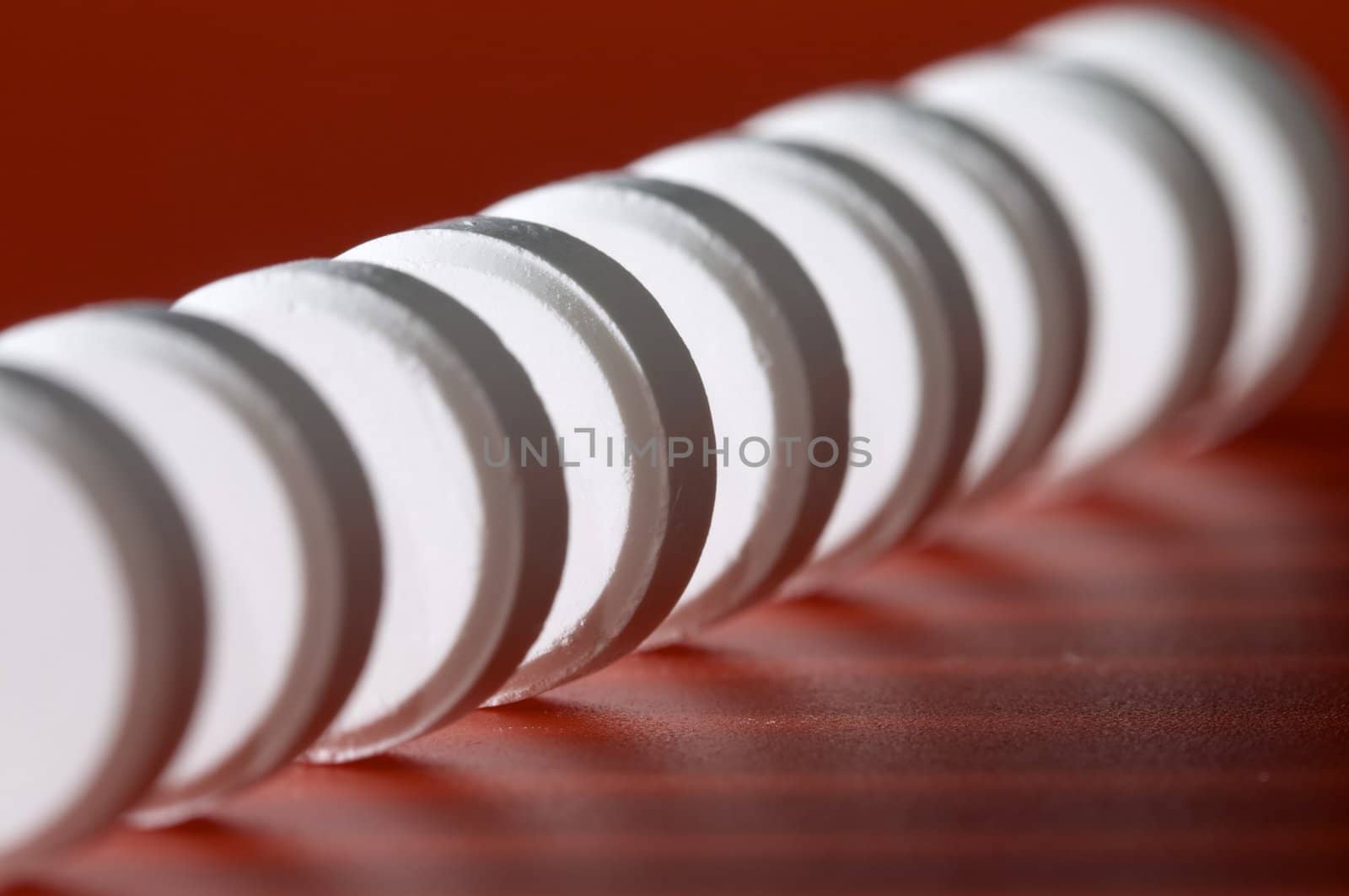 Close-up photo of white pill. Focus on the fourth pill. Shallow DOF