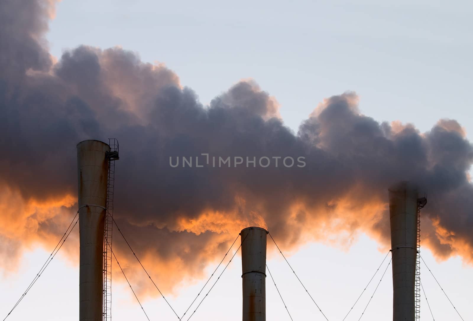 Factory pipes throwing out clouds of orange smoke