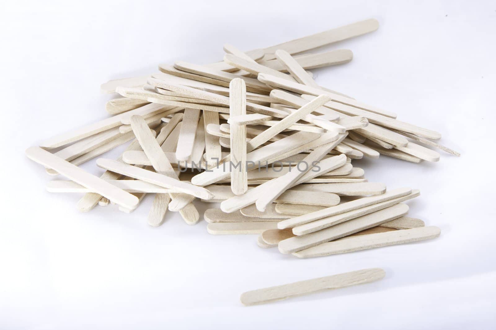 a bunch of wooden icecream sticks lying unarranged on a white surface