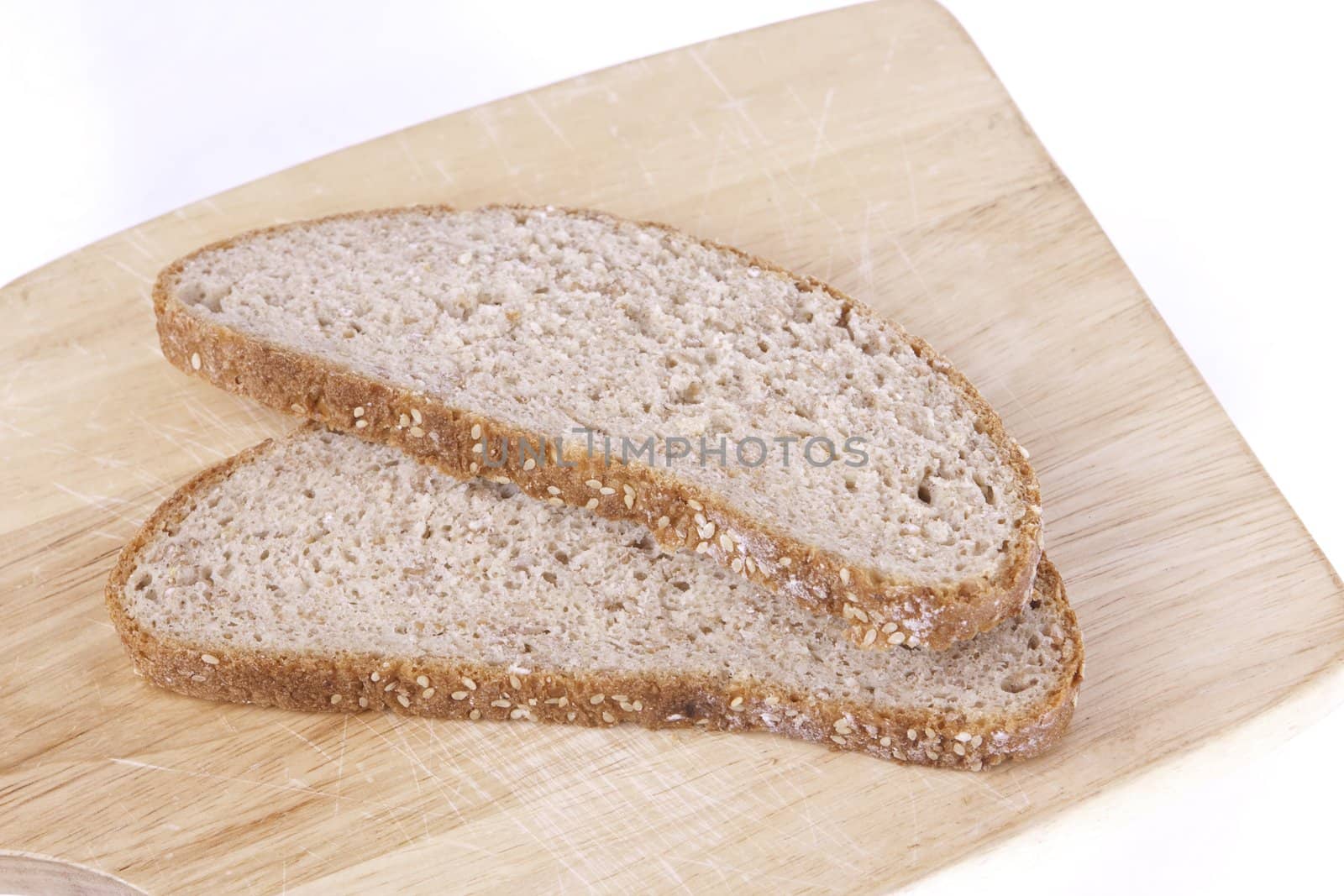 two slices of brown bread lying on a wood board isolated on a white background