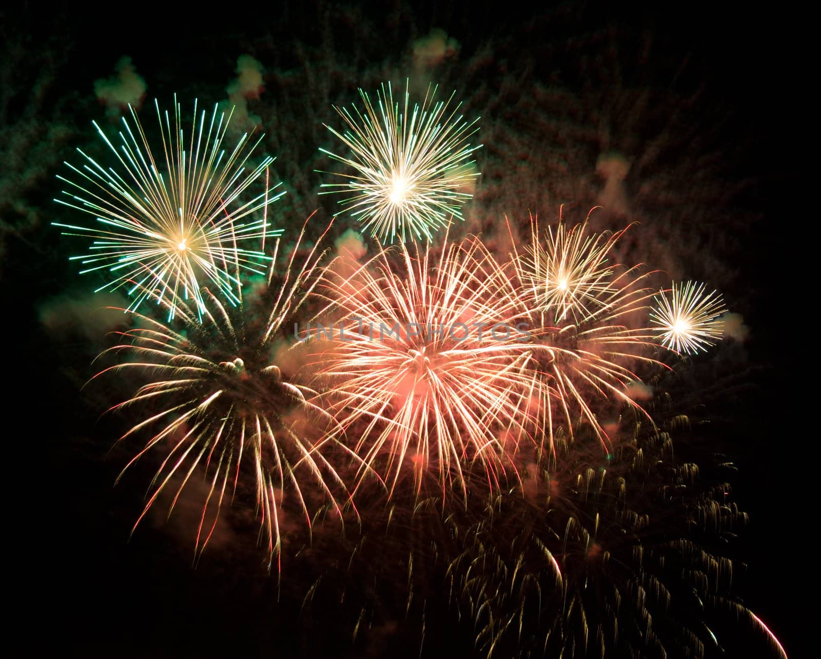 colorful fireworks in night sky and clouds of smoke