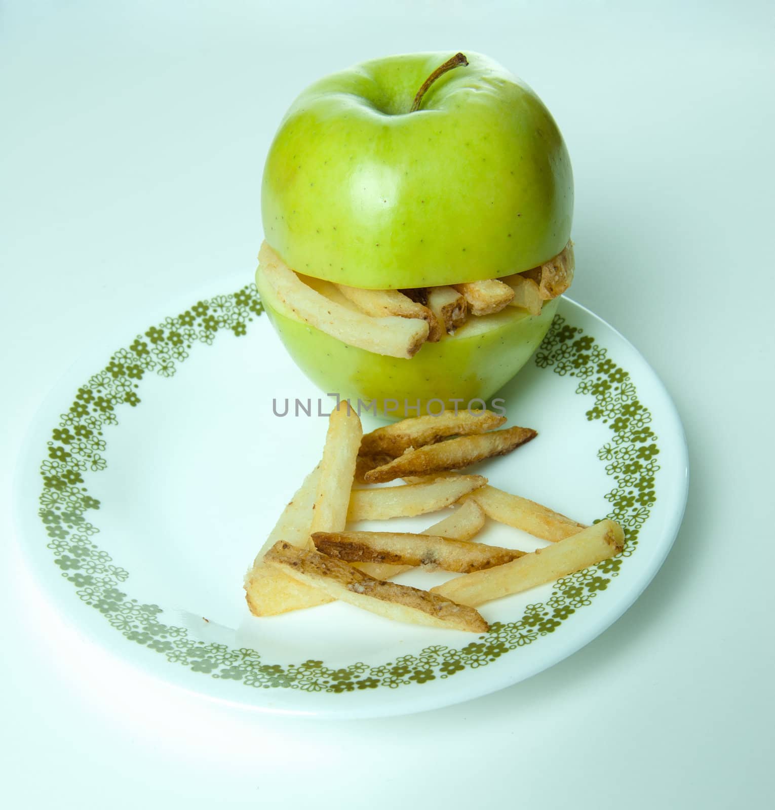 Concept image of unhealthy eating with an apple making a sandwich of french fries.