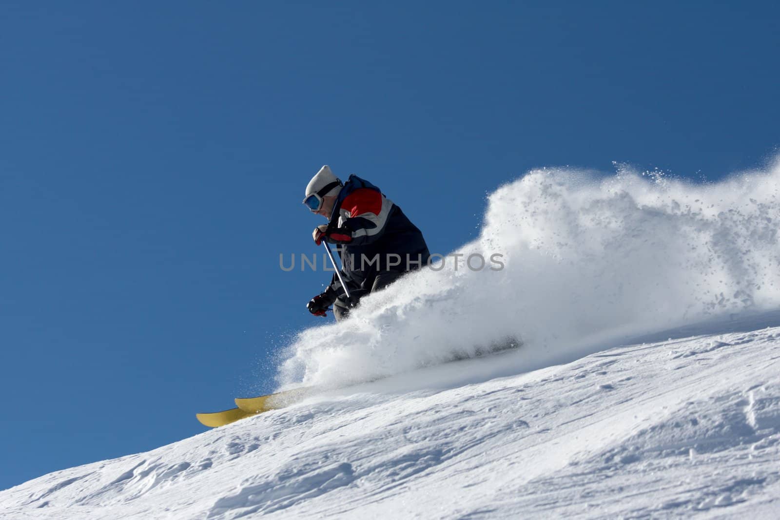 skier in clouds of snow powder against a blue sky