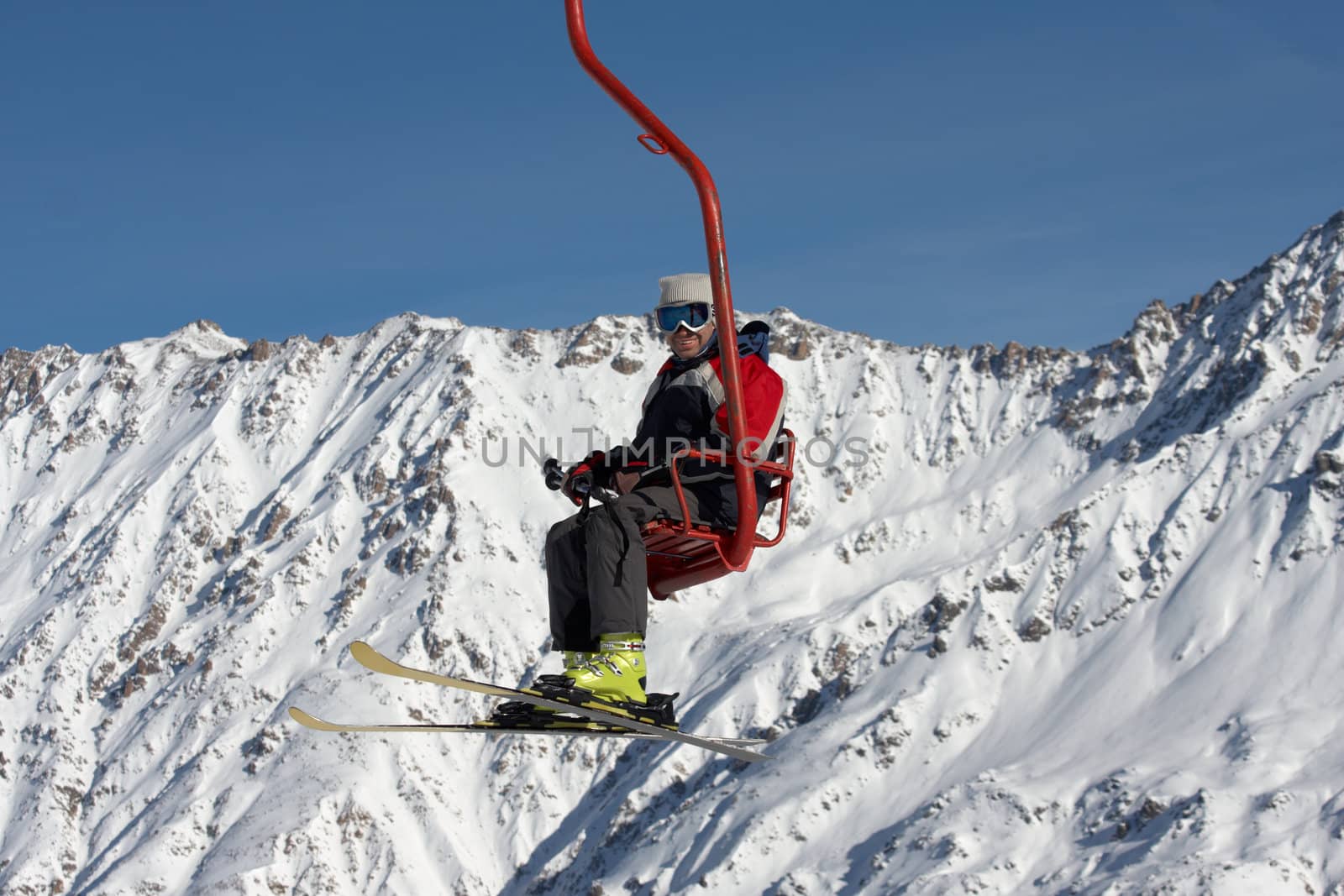 skier mowing up on ski lift under mountains