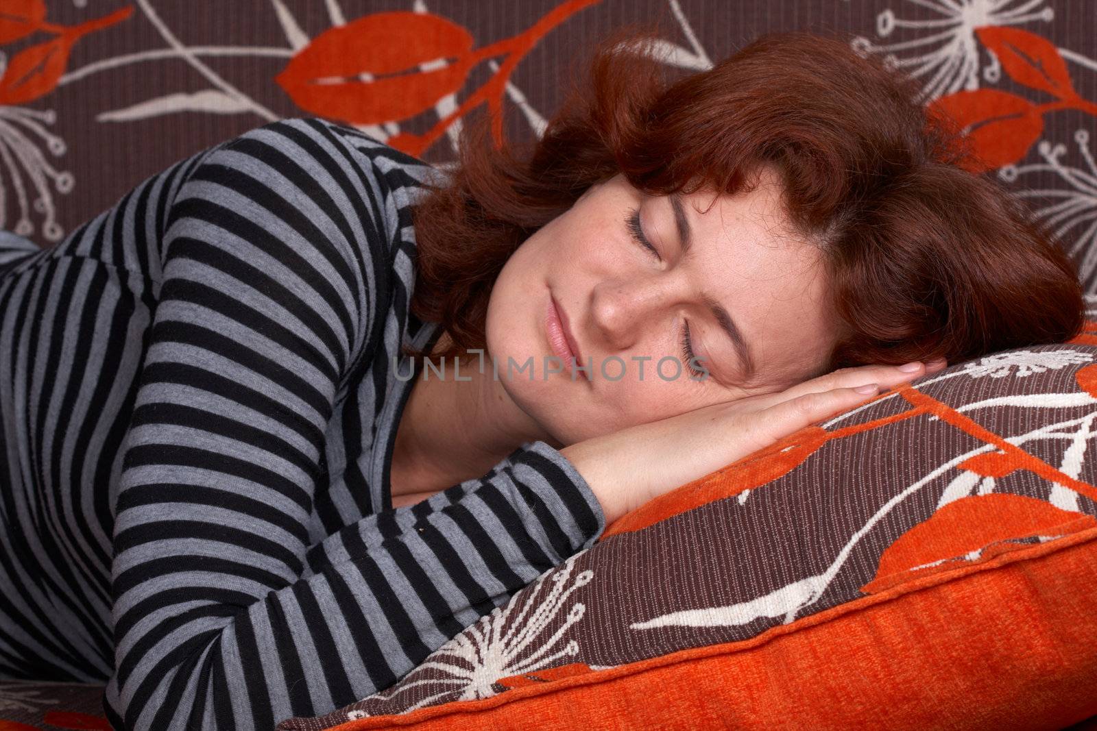 redheaded girl sleeping on orange sofa