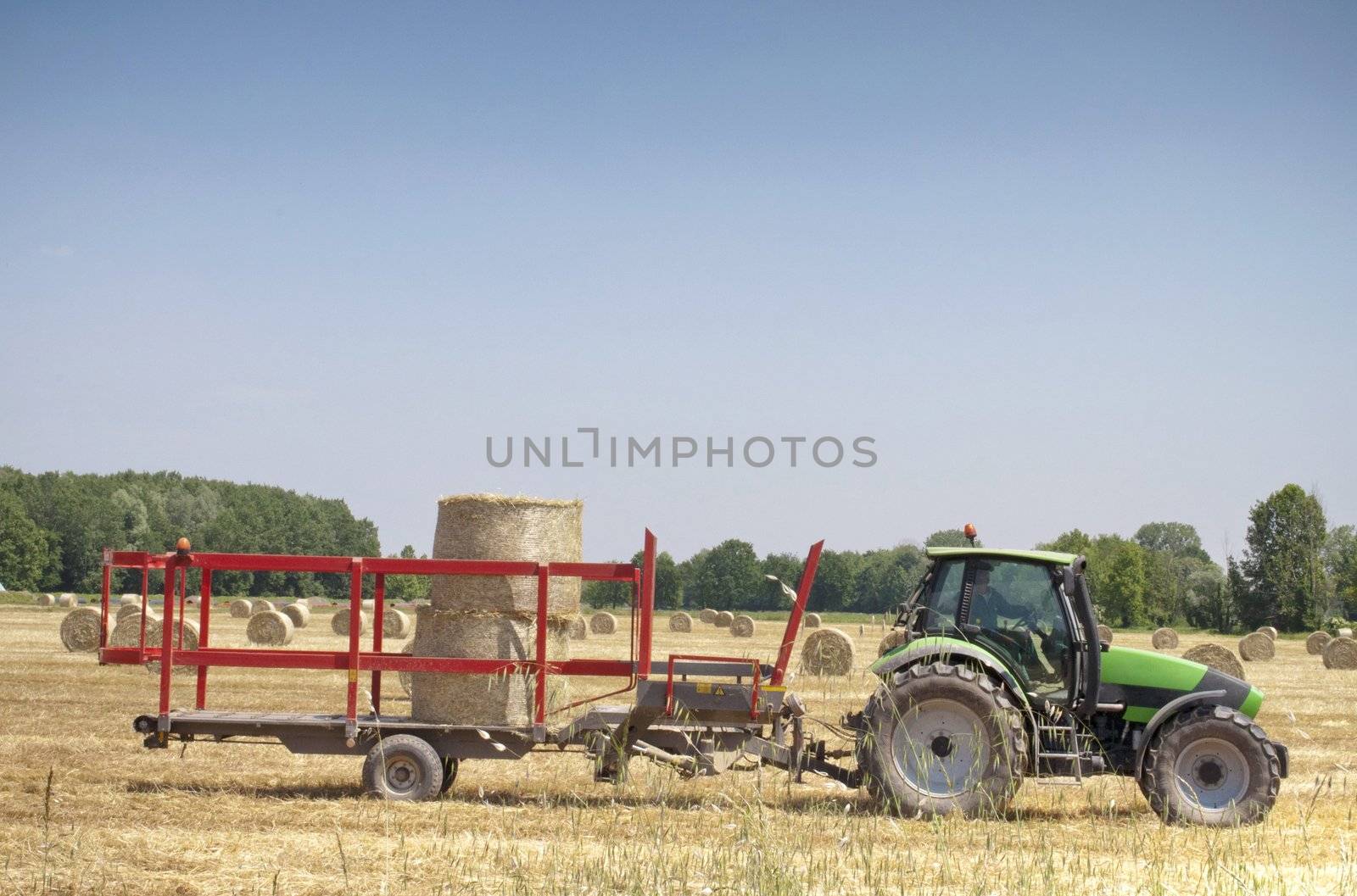 Tractor working on a field, collecting hay balls