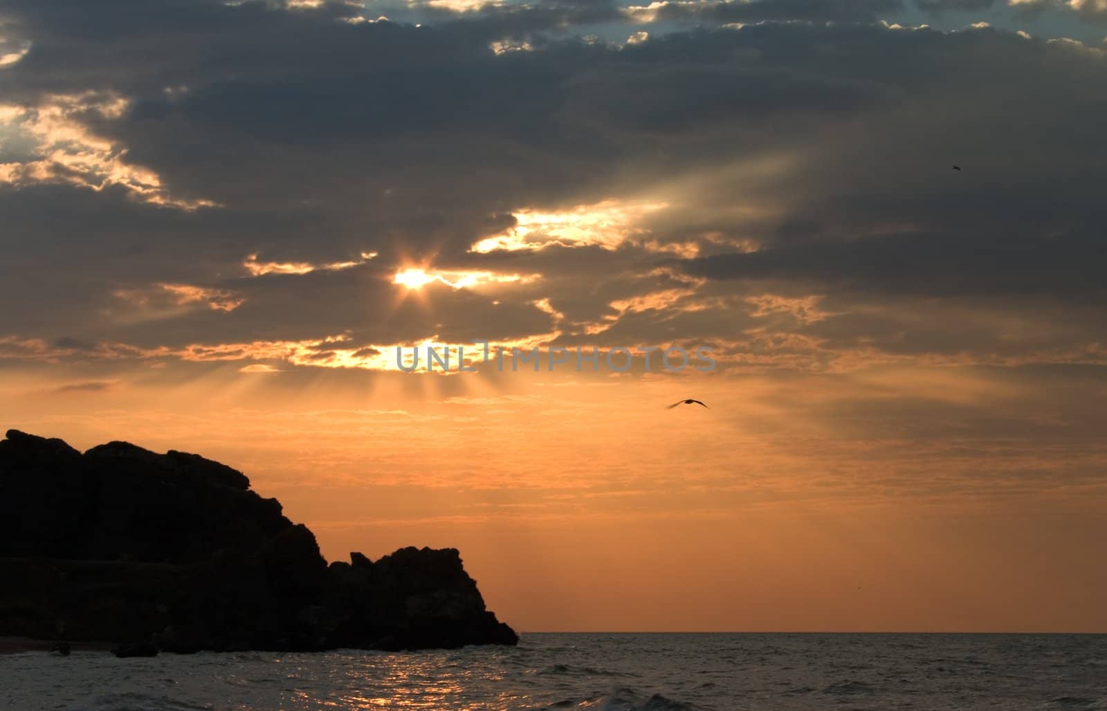 Sunset with sunbeam throw clouds  over sea 