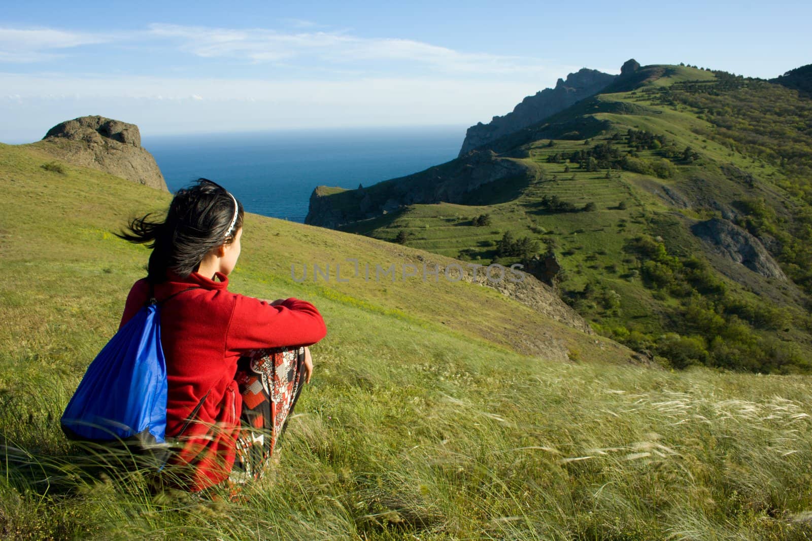 Girl sitting in a grass and looking to the sea