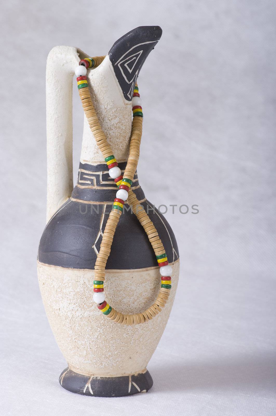 Old-fashioned clay jug with greek ornament and beads