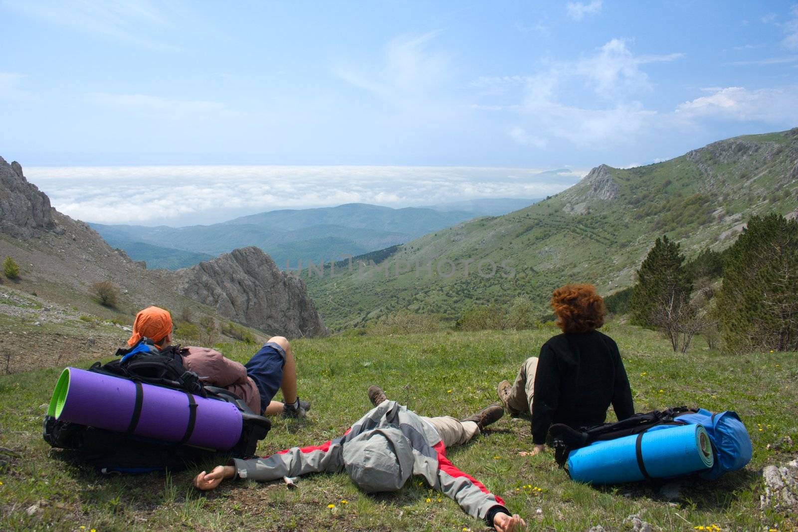 Backpackers relaxing on pass and looking to clouds