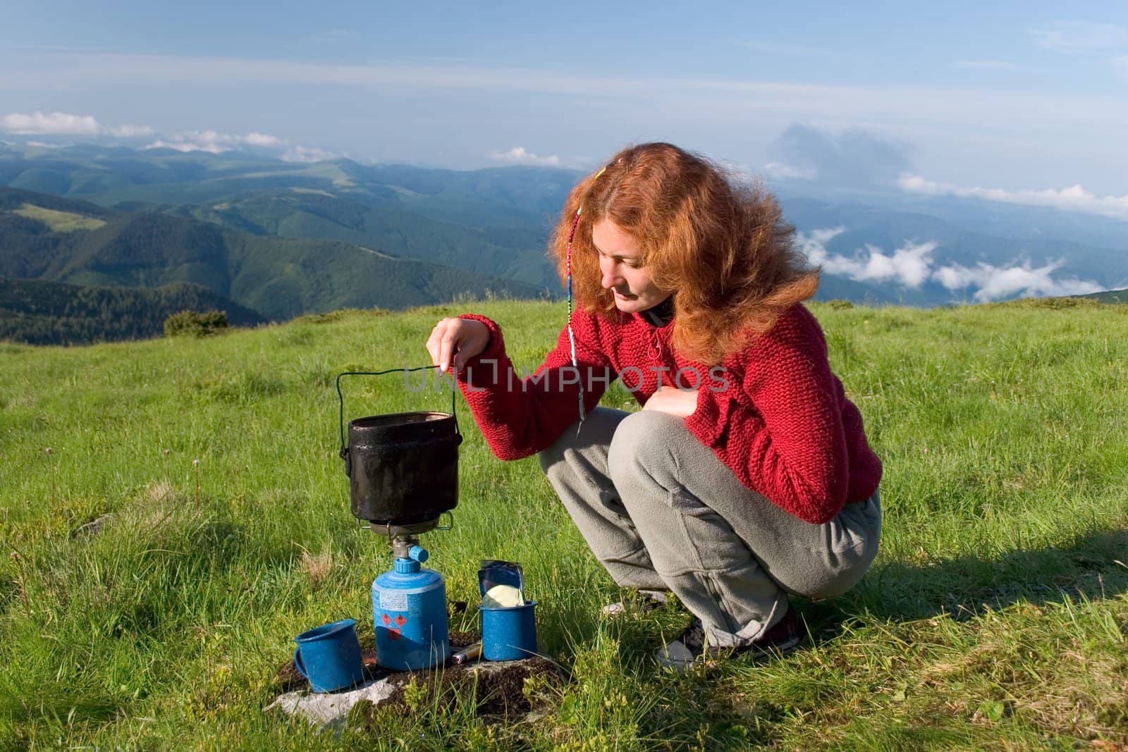 Girl making a coffee in a mountains on gas burner