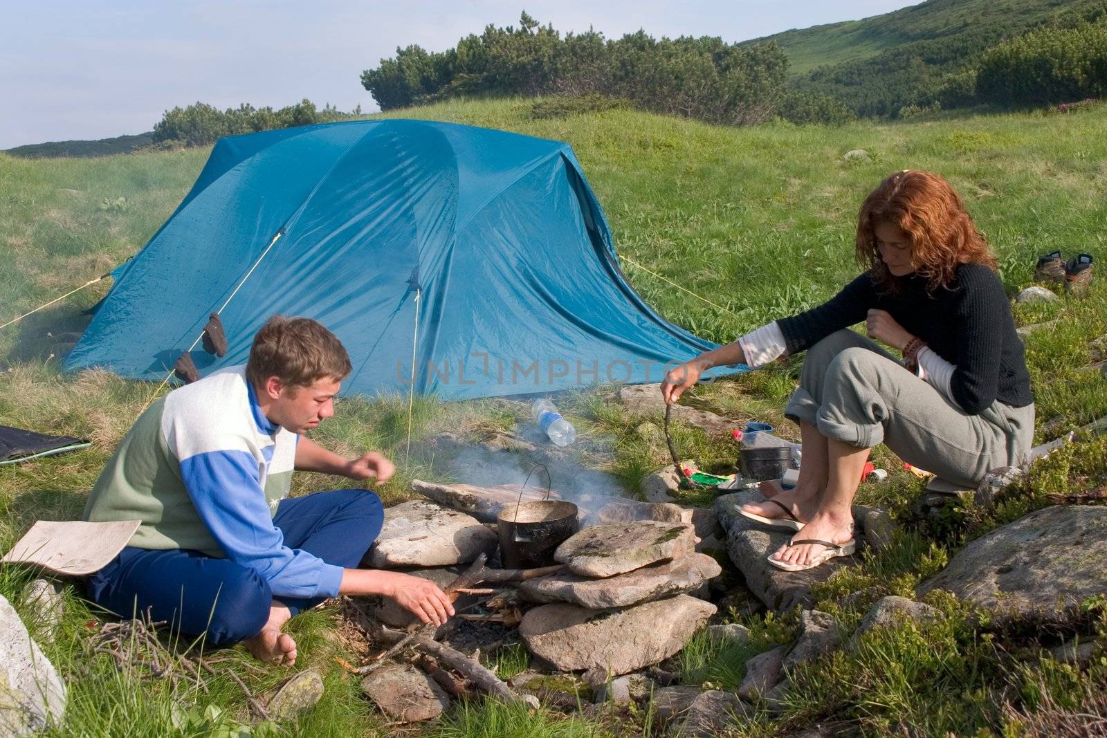 Backpackers preparing food on a fire near of a tent