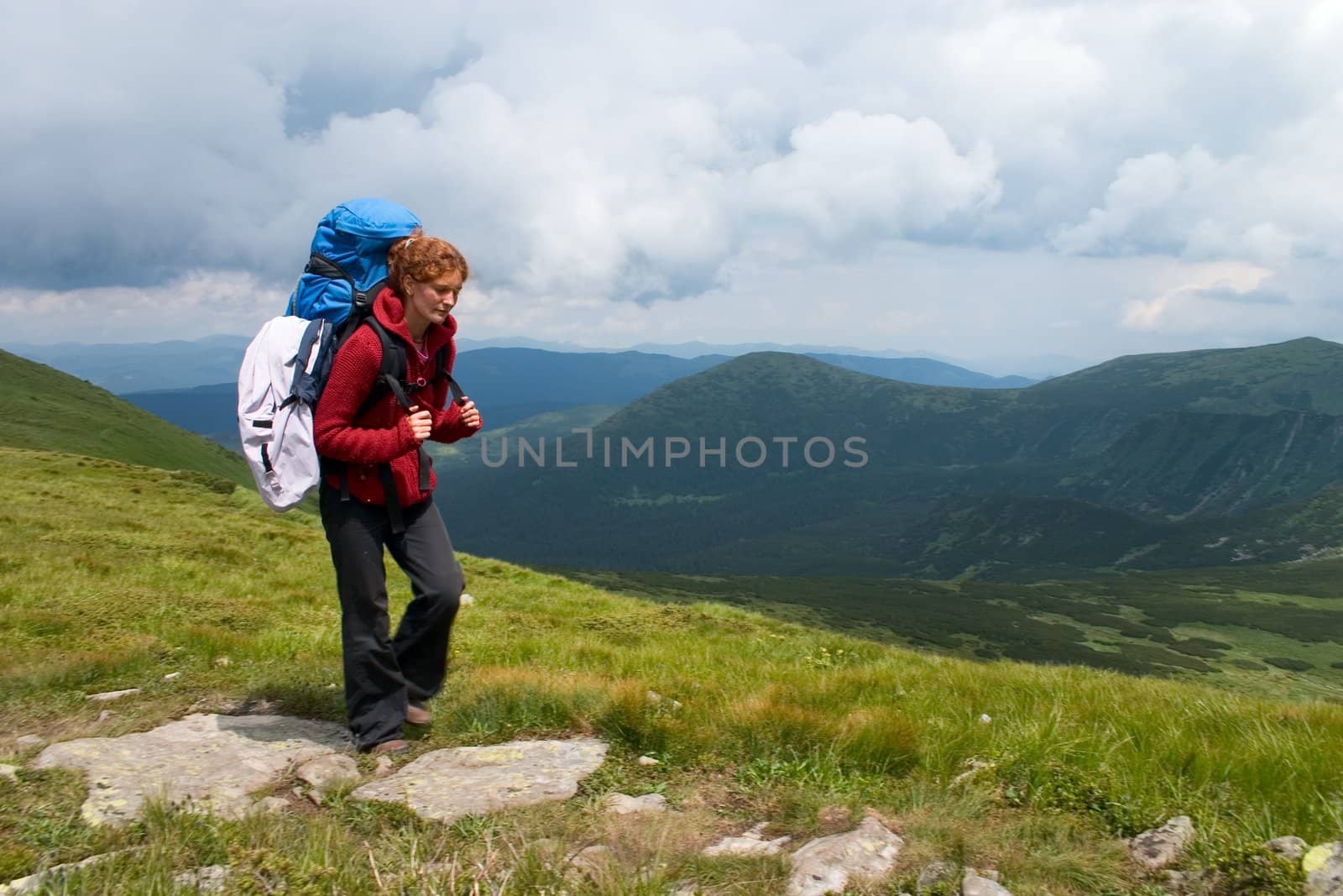 Hiker girl going by track in mountains