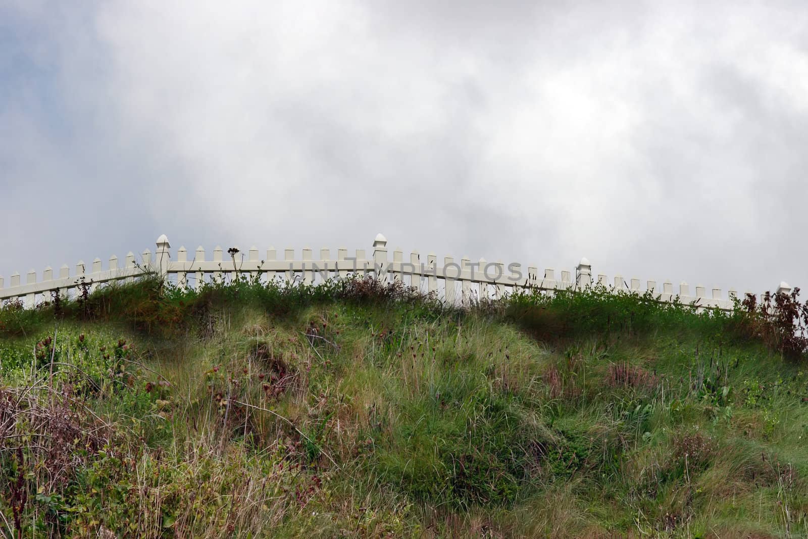 a white picket fence on a grassy hill
