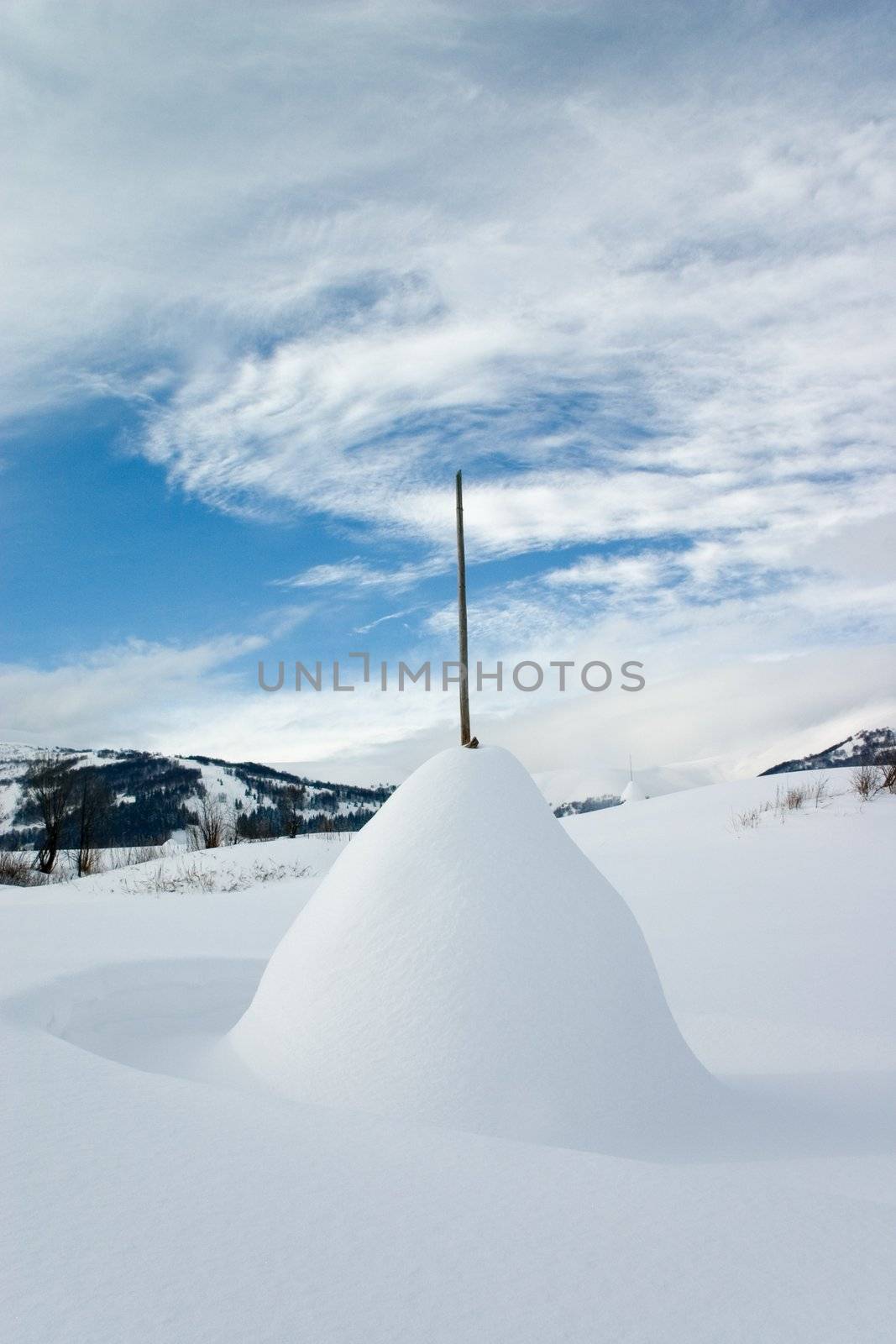 Rick of straw covered with snow on the white snowy plain