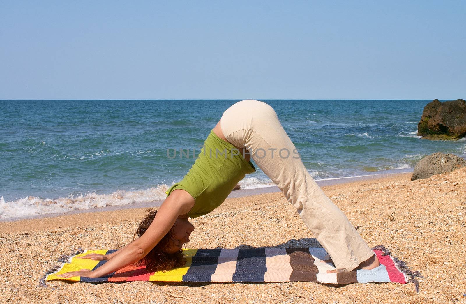 girl doing Adho Mukha Svanasana yoga pose on sea beach