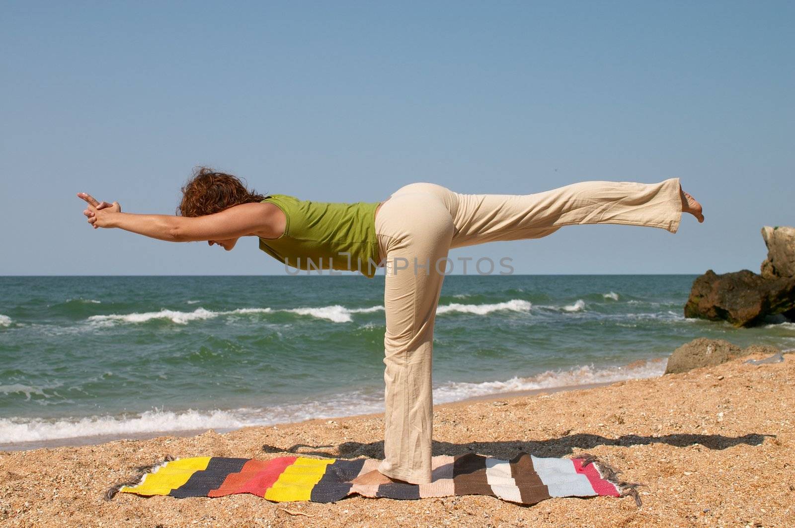 girl doing virabhadrasana yoga pose at sea coast