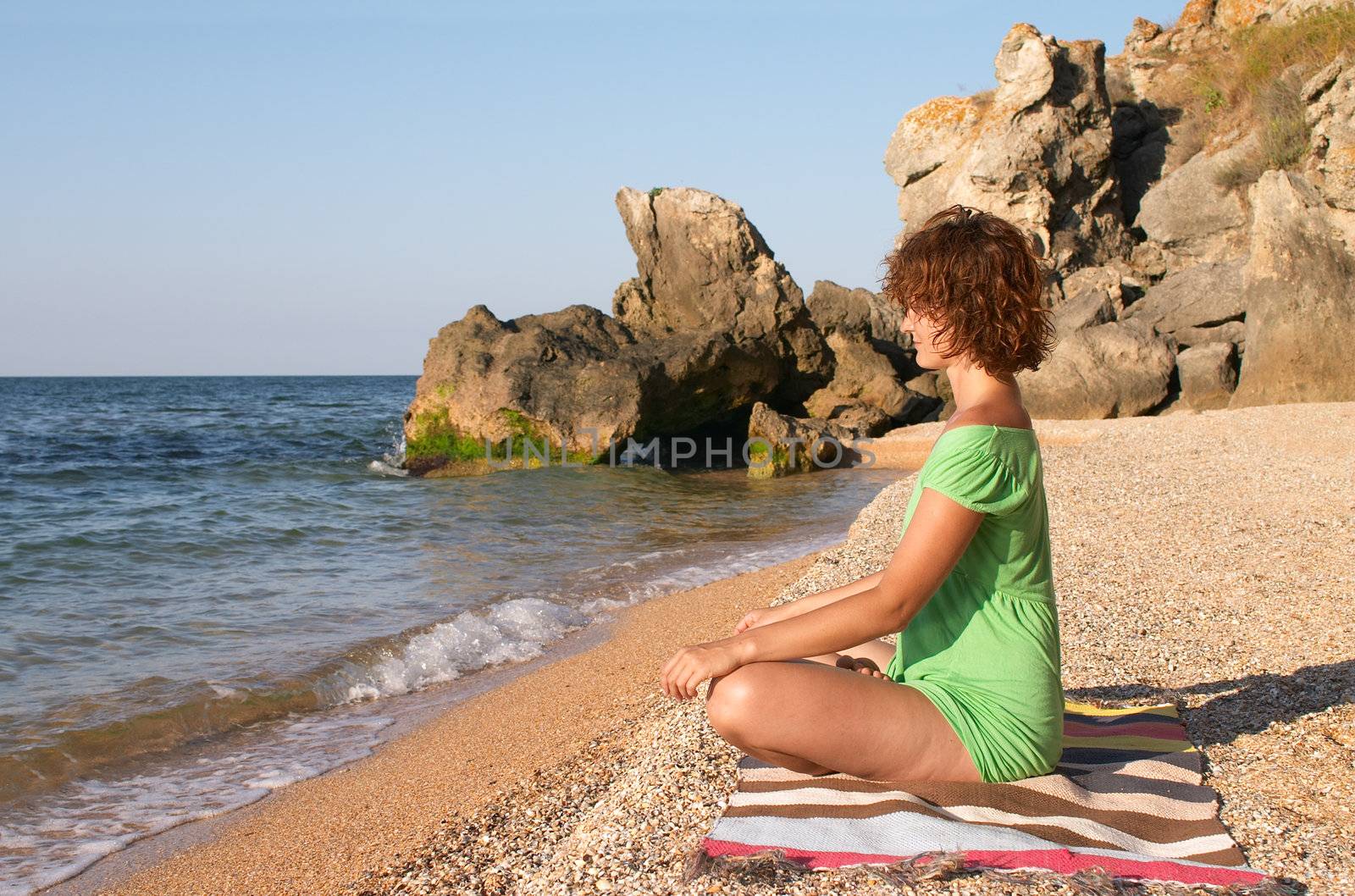 girl practing yoga pose padmasana on the sea coast