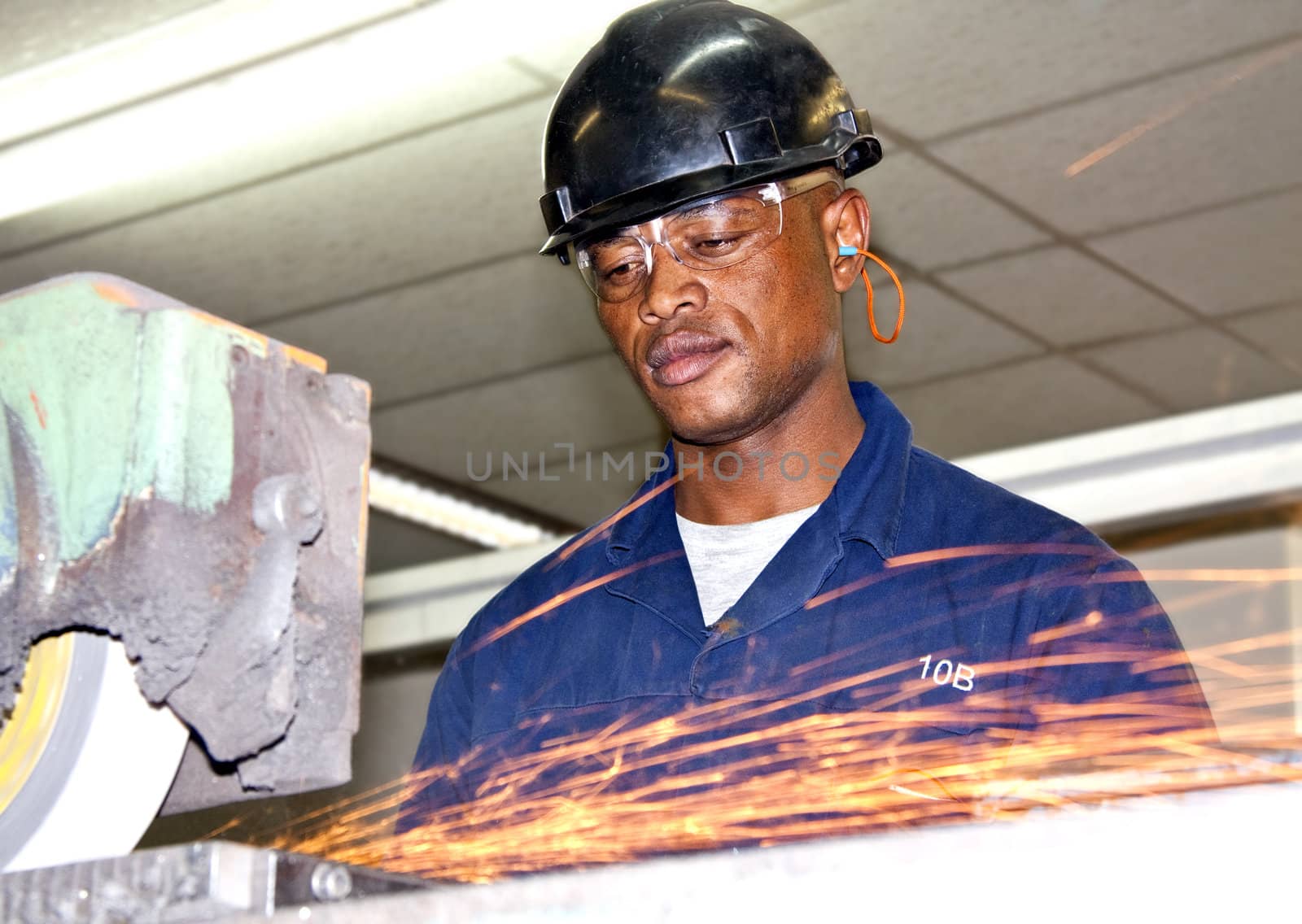 A man grinding a piece of metal in a factory