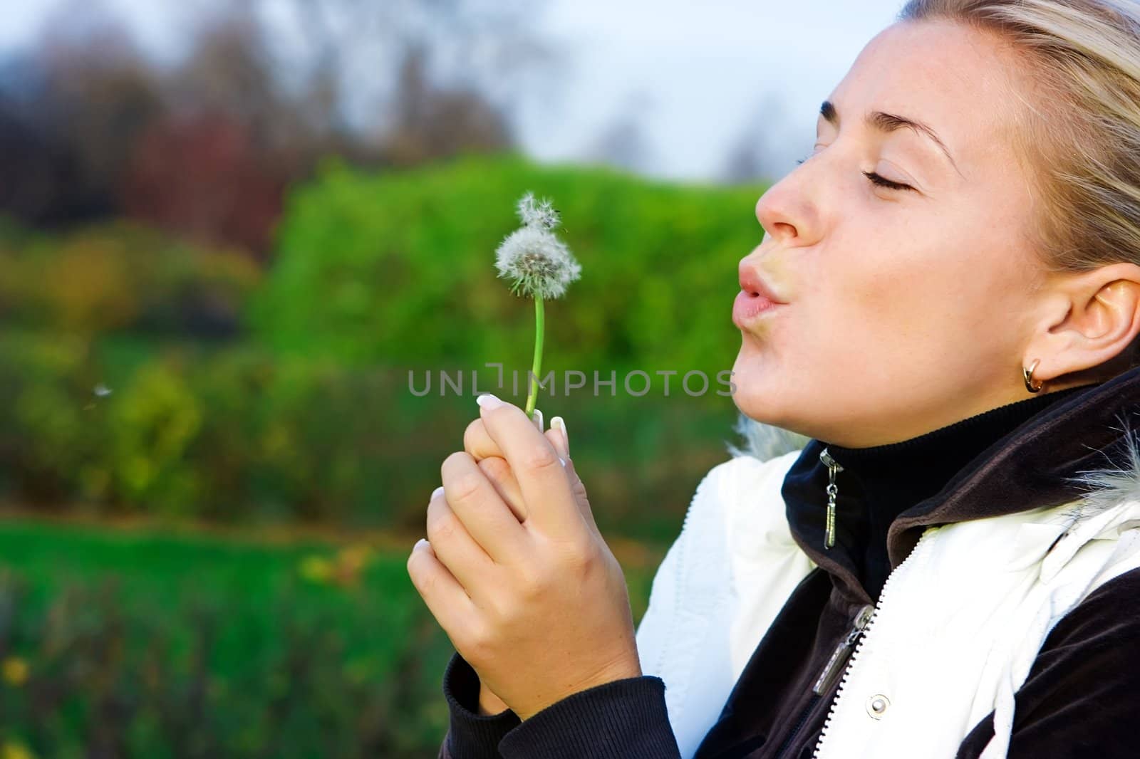 Young girl and dandelion in the countryside