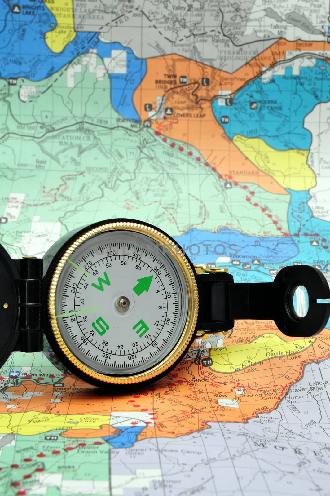 A black lensatic compass on hiking map