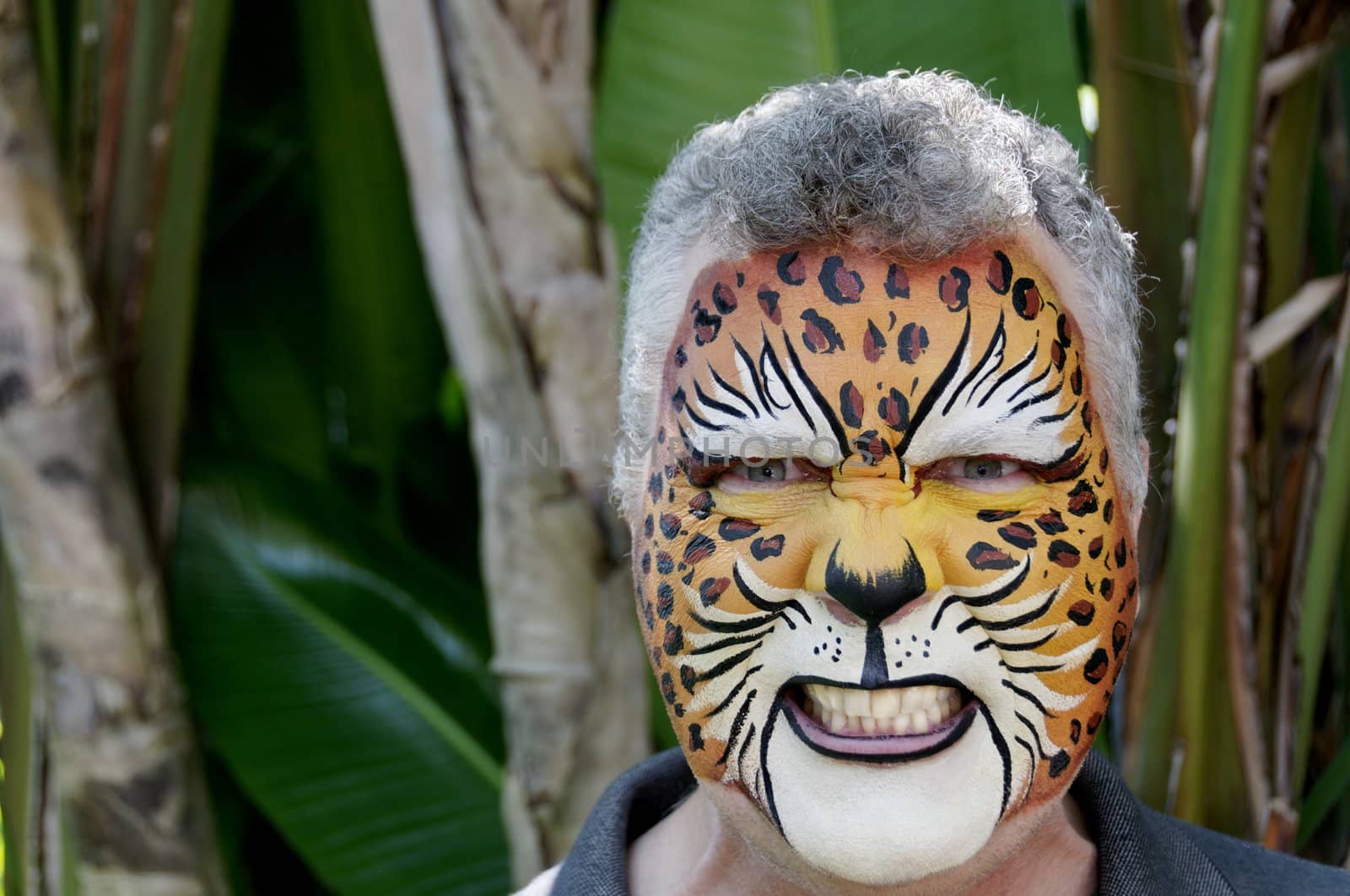 A man with his face painted to look like a leopard, growling.