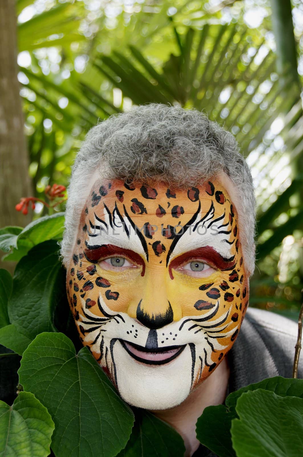 A smiling man with his face painted to look like a leopard.