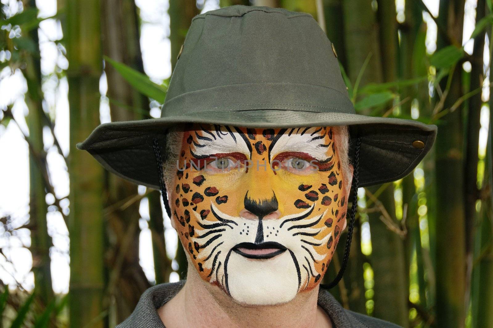 A man with his face painted to look like a leopard wearing a hat.