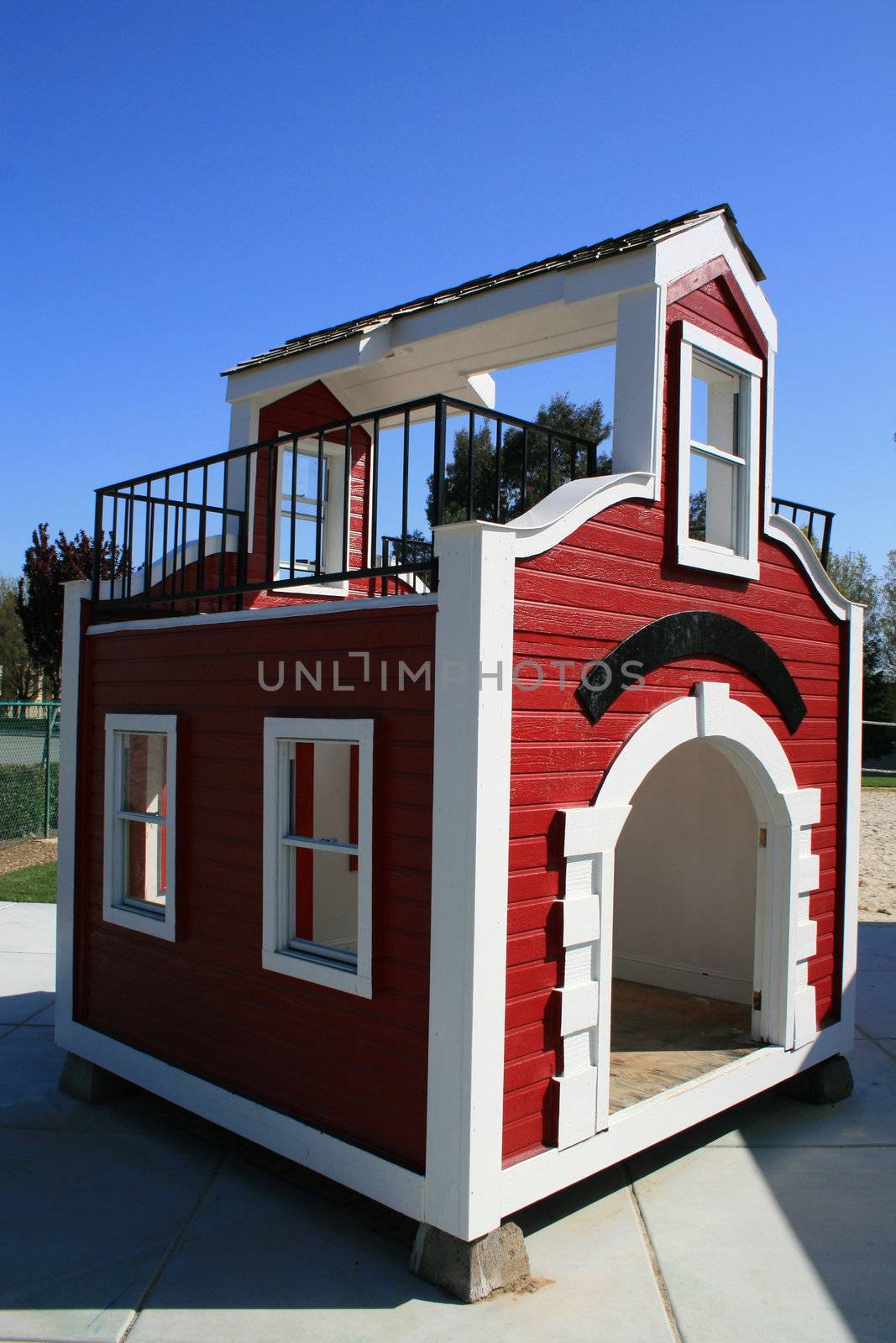 Red and white playhouse on a playground.
