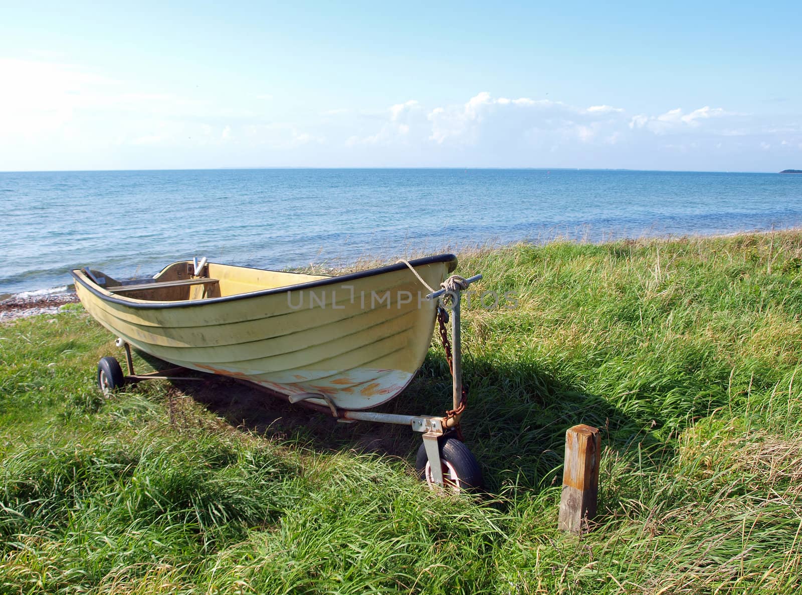 Beach landscape - small colorful skiff on the sand  