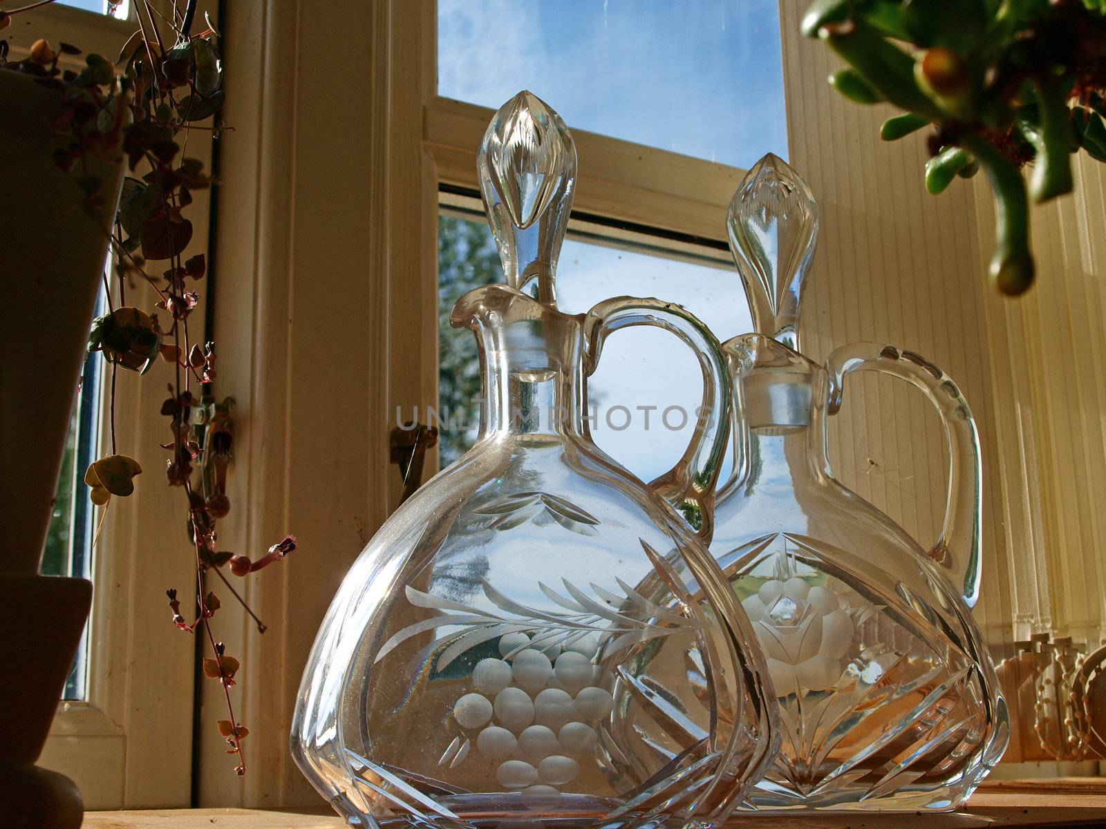 Closeup of Beautiful antique glass carafes bottles in a window shelf      