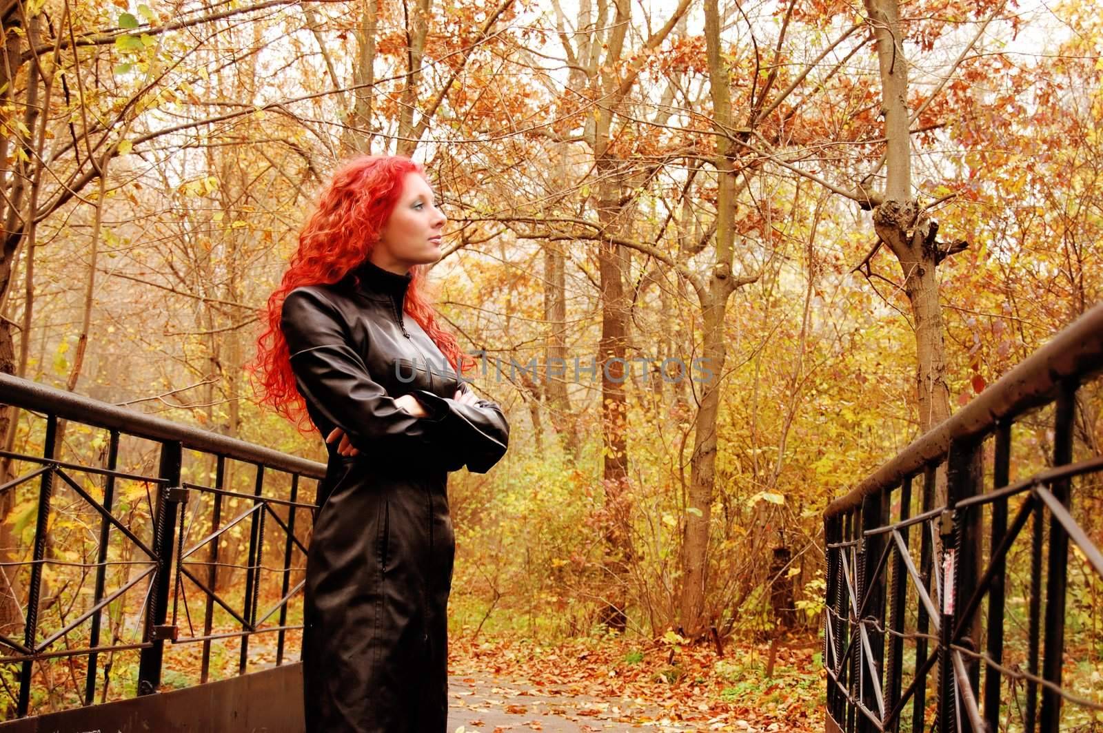 thougthful red hair girl on the bridge in autumn