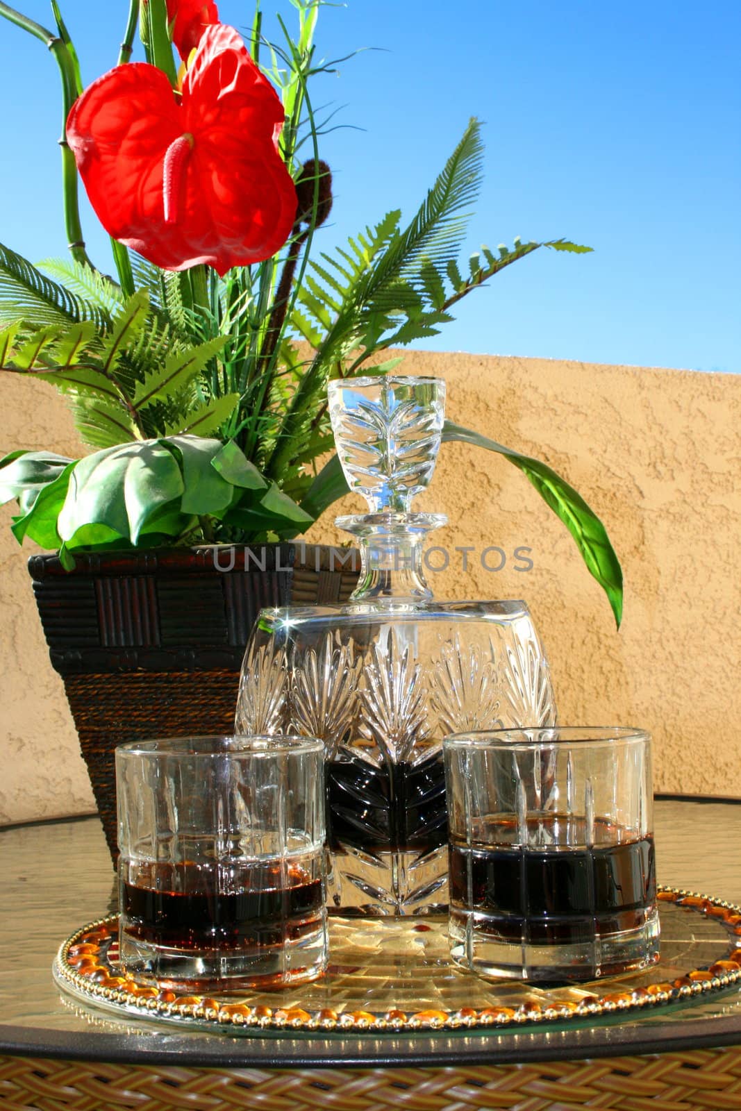 Crystal beverage set with flowers on a glass table.
