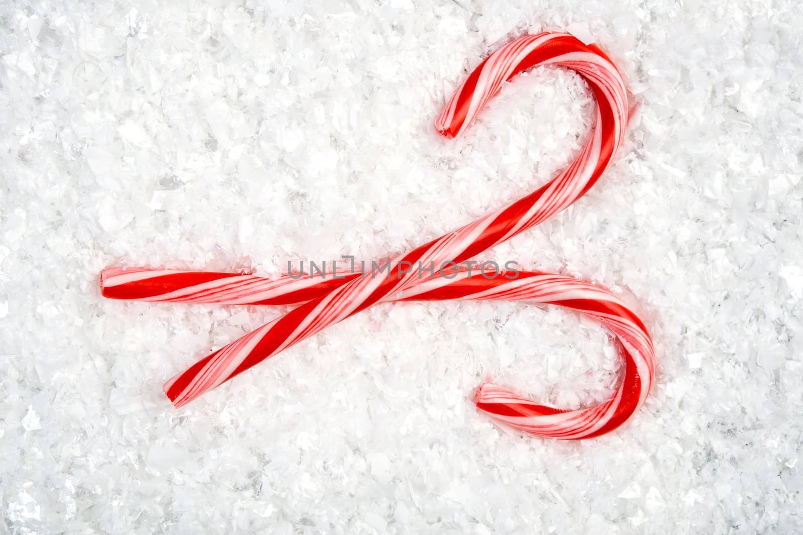 Image of two crossed candy canes lying in the snow