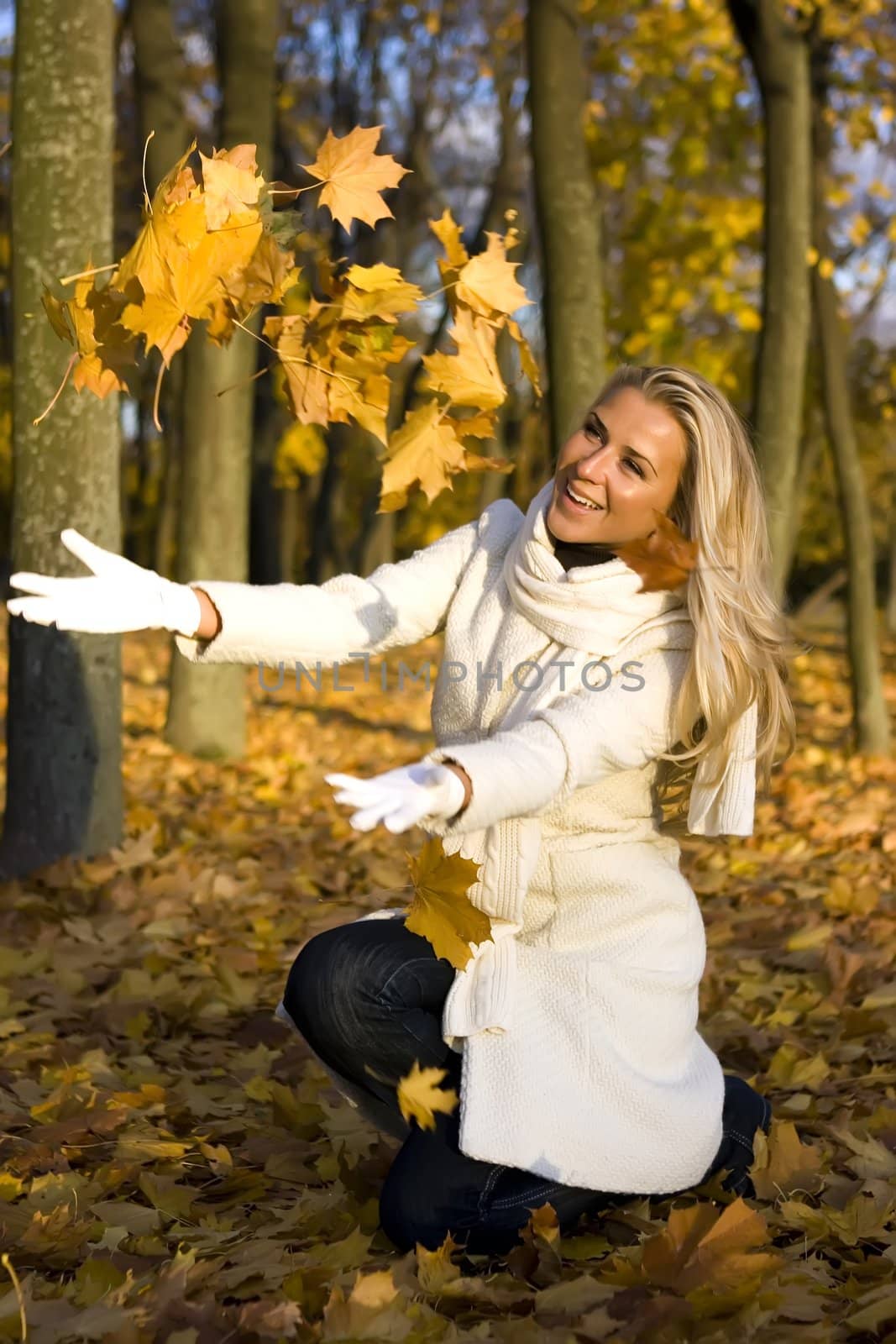 Girl in the park throwing up maple leaves