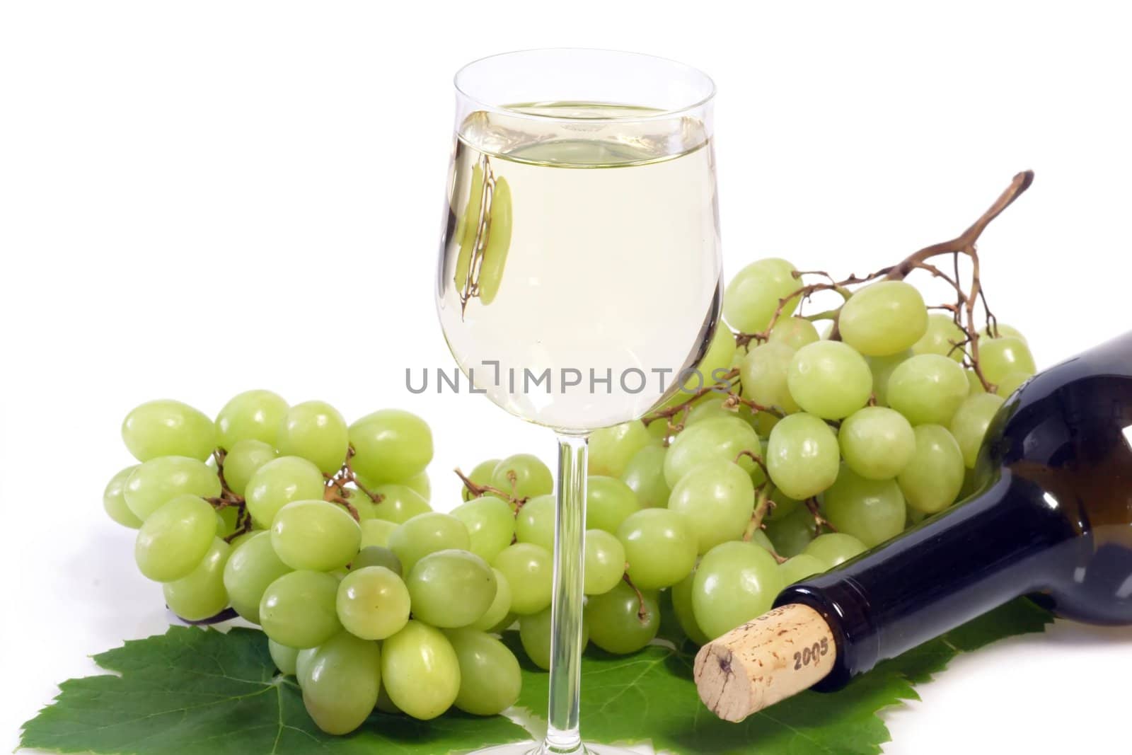 Glass of white wine with bottle and grapes on bright background