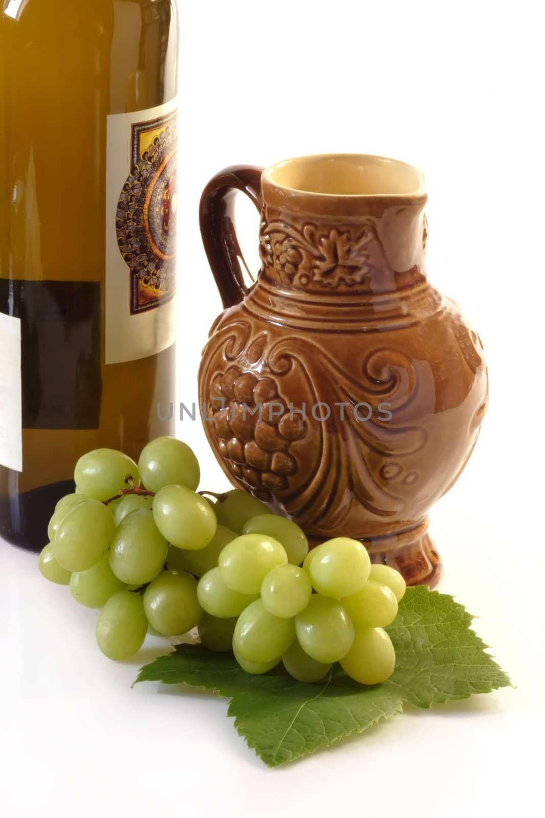 Wine jug, grapes and bottle on bright background