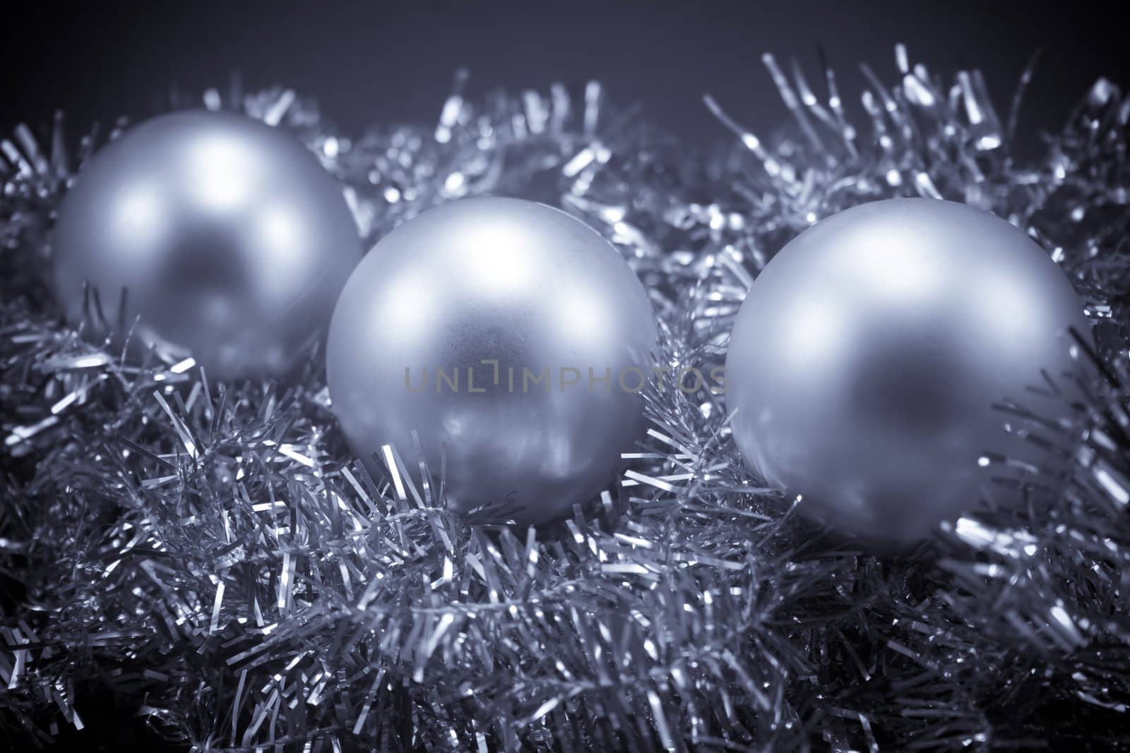 Three Christmas globes laying on tinsel
