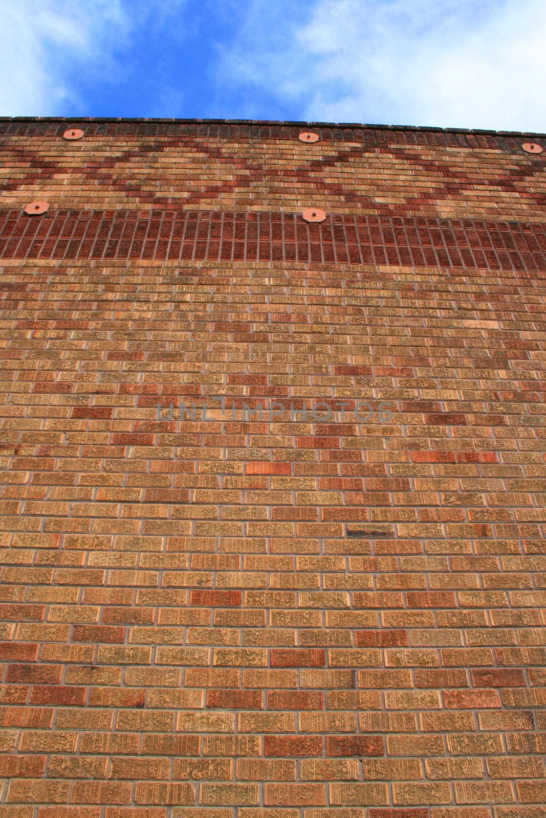 Brickwall over blue sky showing unique pattern.
