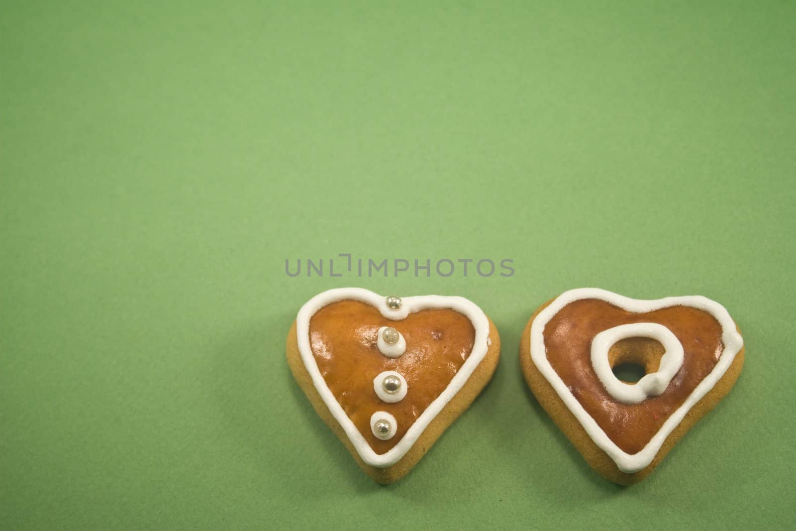 Two Christmas cookies against green background ad space above
