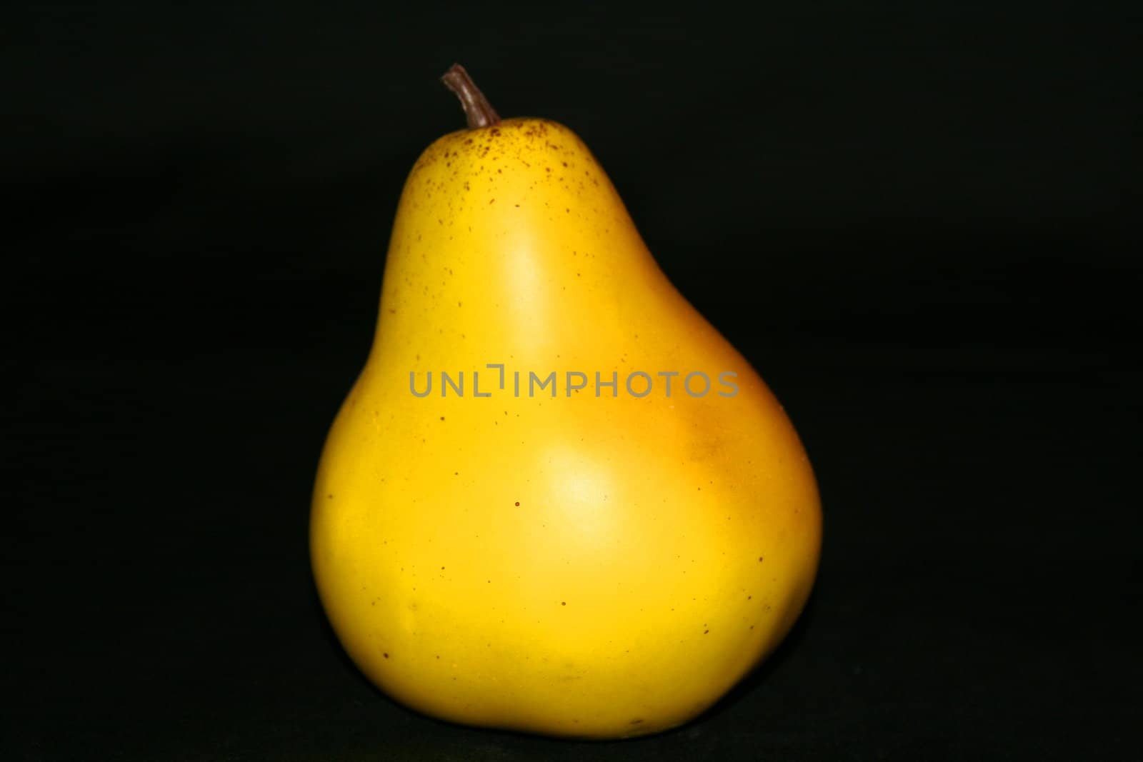 Yellow ripe pear on a black background.
